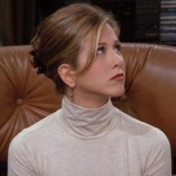 Rachel Green with hair tied up sitting on a couch at central perk cafe 