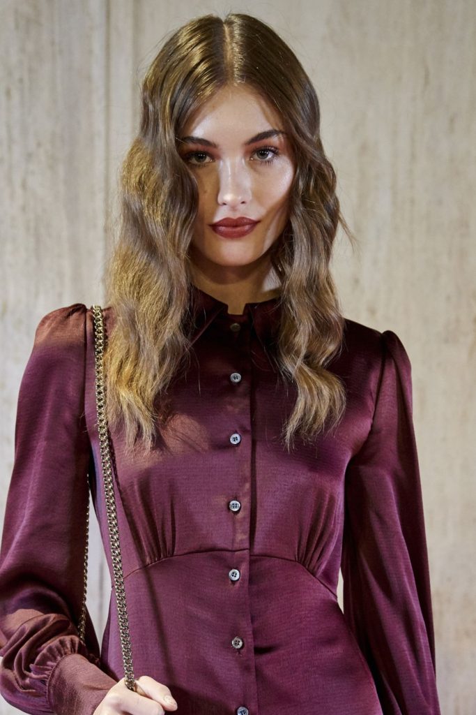 Model in a plum silky dress sporting a mixed texture hairstyle 