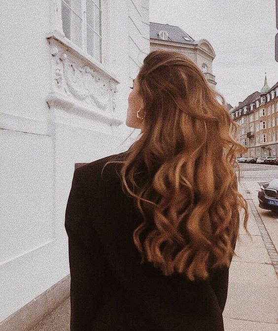 girl with long brown wavy hair walking in a city 