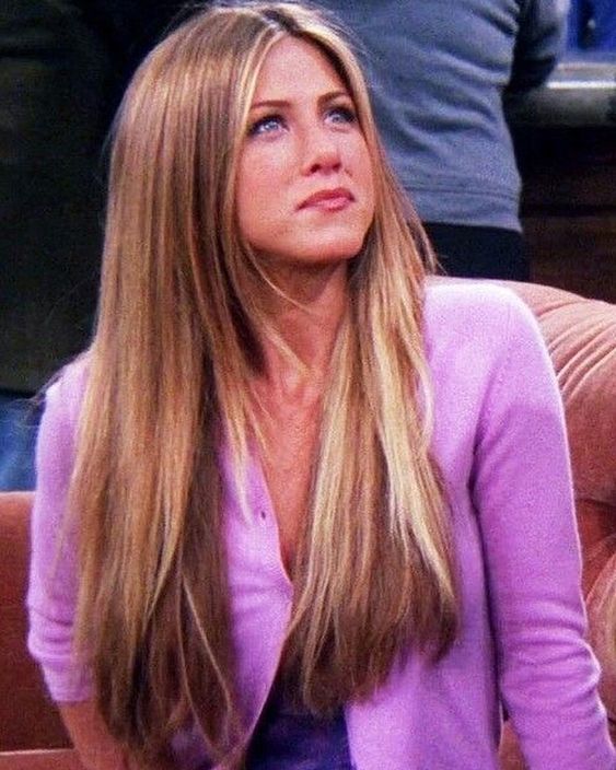 Rachel Green smiling with long blonde hair in Central Perk cafe 