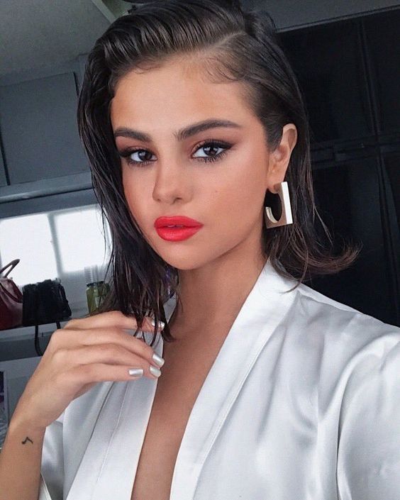 Selfie of Selena Gomez with red lipstick and short hair in a slicked back wet hair look