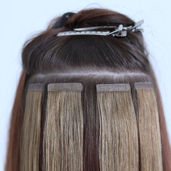 A photo of tape in extensions applied to a girls hair. 